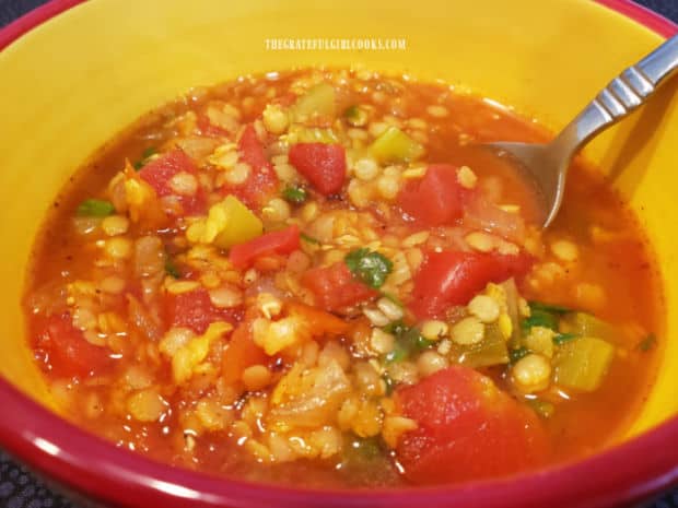 A red and yellow bowl, filled with one serving of Mexican red lentil soup.