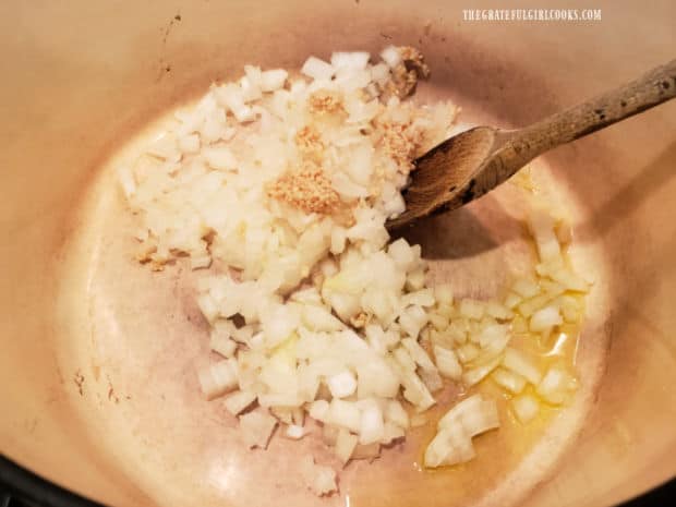 Chopped onion and minced garlic are cooked in olive oil in a large pot.