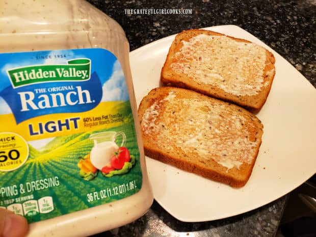 Toasted bread is spread with ranch salad dressing before making the sandwich.