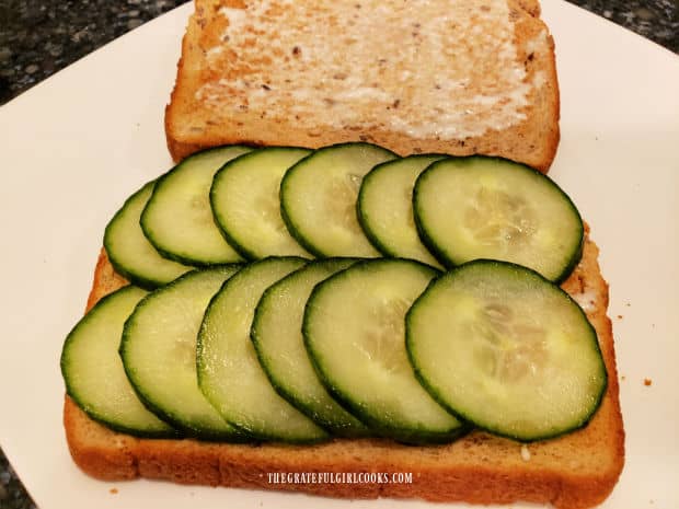 The thin cucumber slices are placed on one piece of toasted bread.