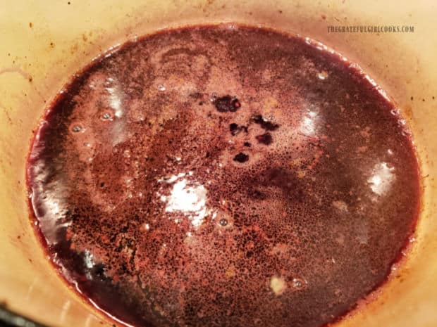 Red wine and minced garlic cook in large pan until reduced in volume.