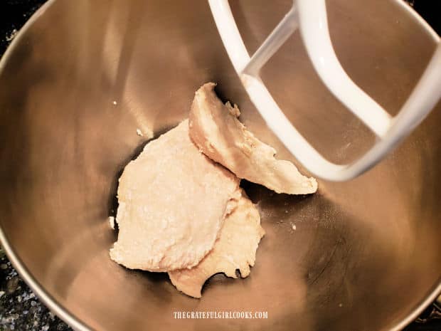 Cooked boneless, skinless chicken breasts are placed in a stand mixer to shred.