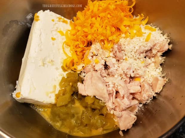 Shredded chicken, green chiles, cream cheese and grated cheese in metal bowl.