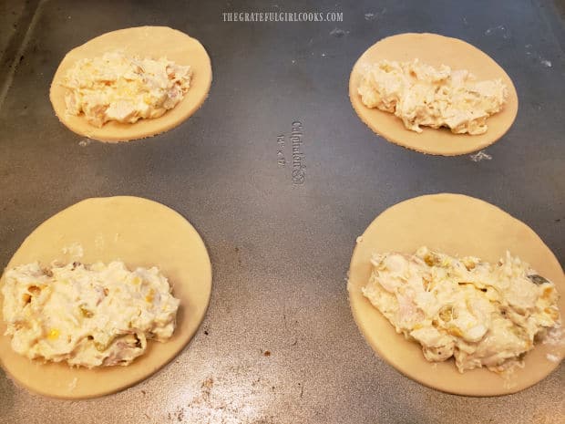 Half of each dough circle is covered with chicken suizas filling.
