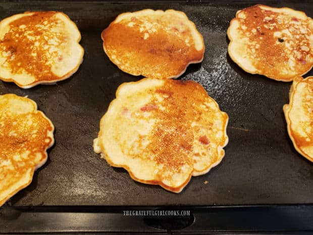 The strawberry oatmeal pancakes are browned on the bottom, then flipped.