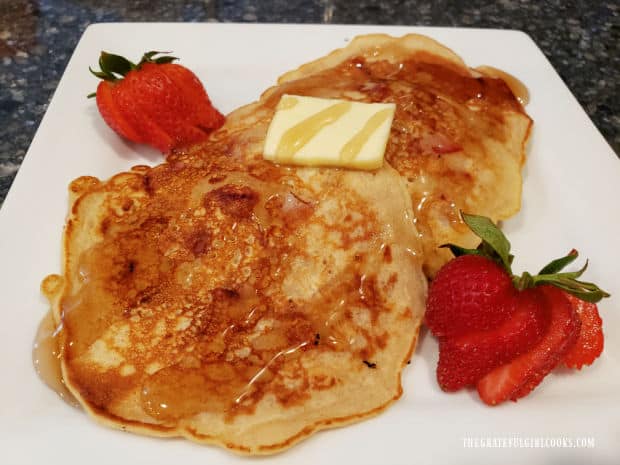 Plate of strawberry oatmeal pancakes, with butter, syrup and fresh strawberries.