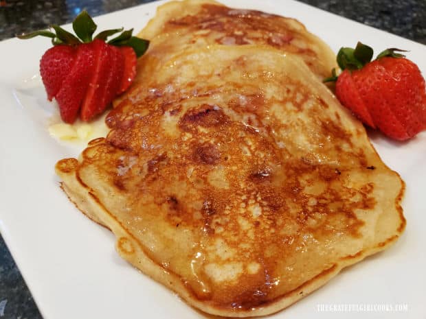 A close up of one of the pancakes, with two strawberries on the side.