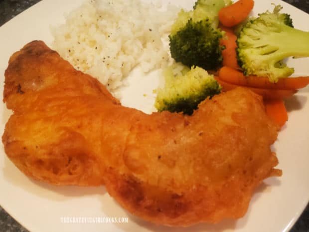 A piece of batter-fried rockfish, served with rice and mixed vegetables.