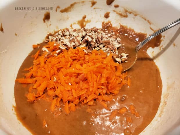 Grated carrots and chopped nuts are added to the bread batter in the bowl.