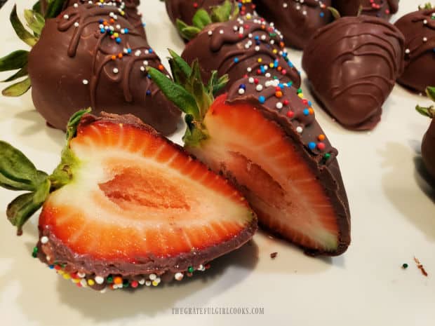 A chocolate covered strawberry sliced in half to reveal the inside.