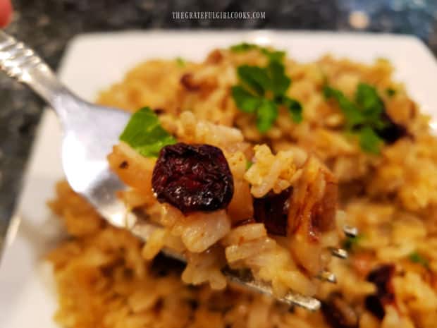 A forkful of the cranberry pecan curried rice, with the remaining rice in the background.