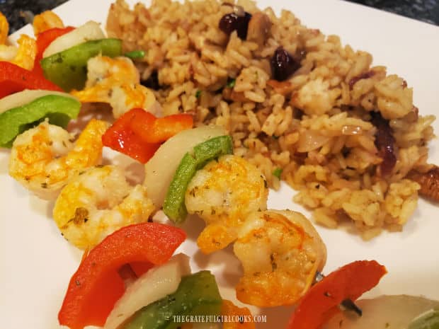 Shrimp kabobs on a plate, with the cranberry pecan curried rice on the side.