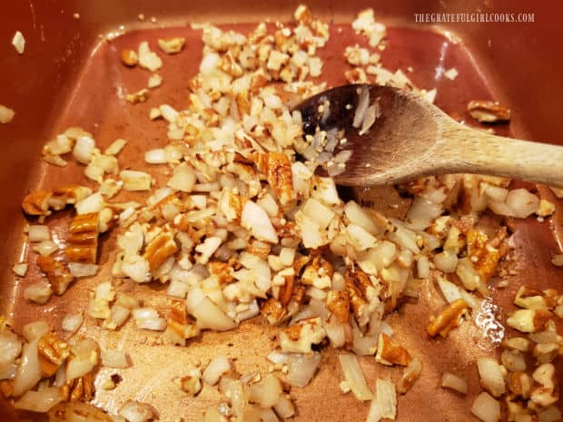 Minced garlic and chopped pecans are added to the cooked onion in the pan.