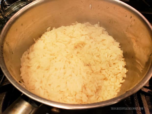 Once fully cooked, the pan of rice is fluffed using a fork.