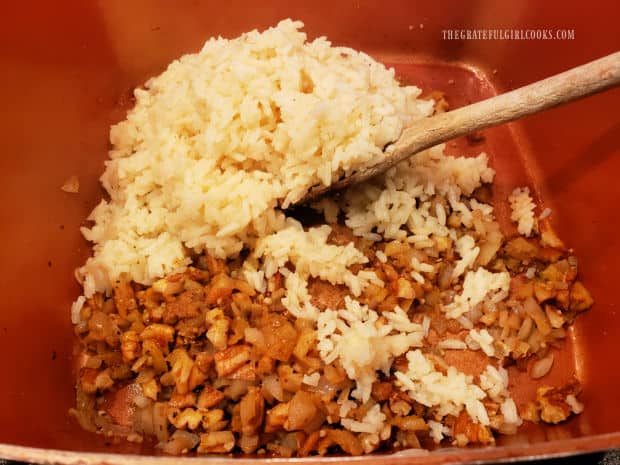 Cooked rice and water are added to the saucepan, and combined with the onion mixture.