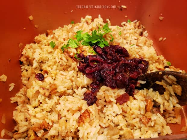 Dried cranberries and chopped parsley are added to the rice and stirred to combine.