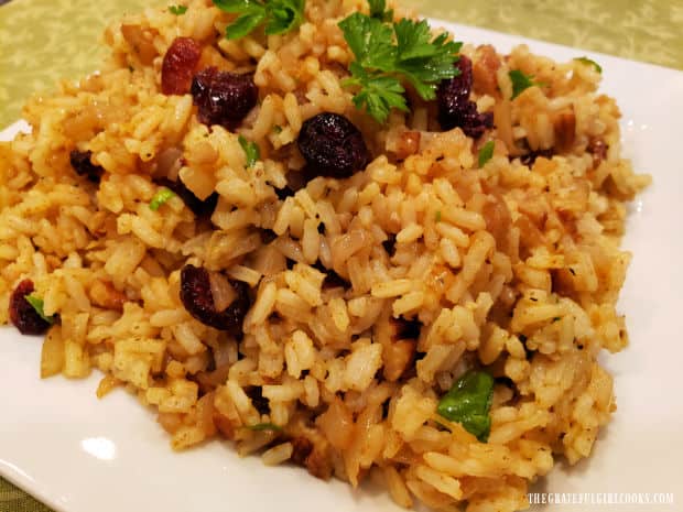 Cranberry Pecan Curried Rice is garnished with fresh parsley and served on a platter.