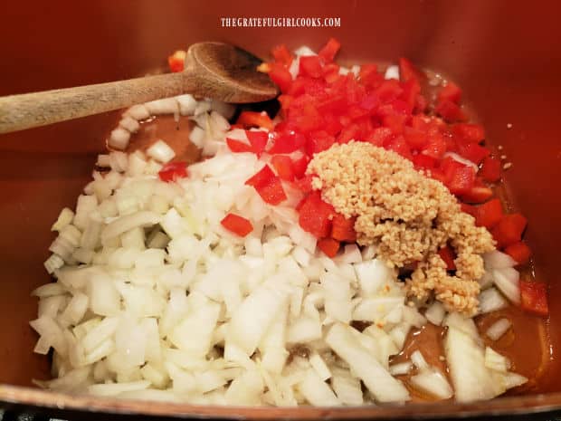 Chopped red bell peppers, onions and minced garlic cook in the pan.