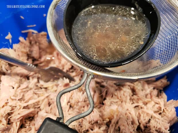 Juices from slow cooker are strainer into the pulled pork, to add additional flavor and moisture.