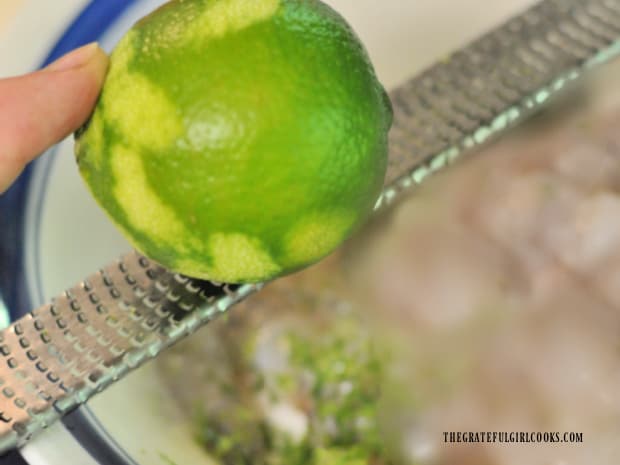 Using a microplane to extract lime zest from outer peel of the lime.