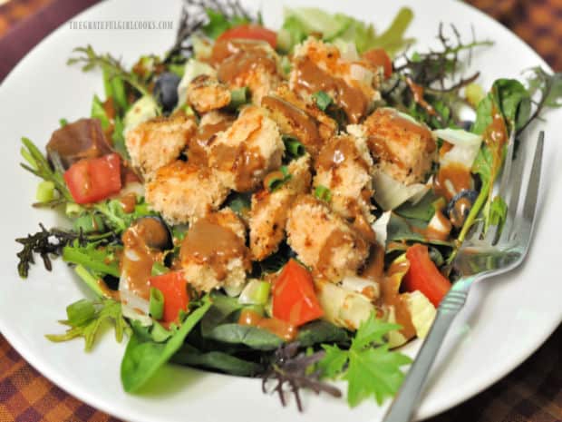 Hoisin vinaigrette for salads, on mixed greens with chicken, in white bowl.