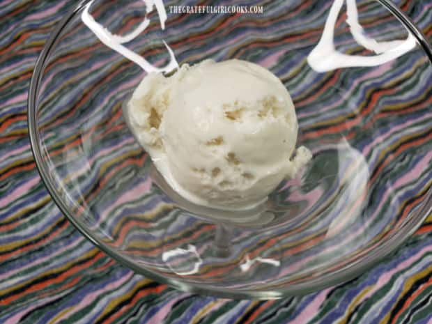 A scoop of vanilla ice cream is placed in glass dish to start making the sundae.
