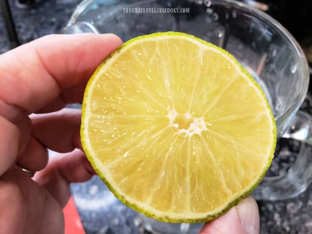The juice of one lime is added to a pitcher full of water.