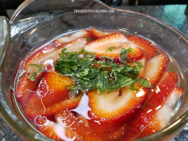 Some mint leaves are crushed then added to the strawberry mint lime agua fresca.