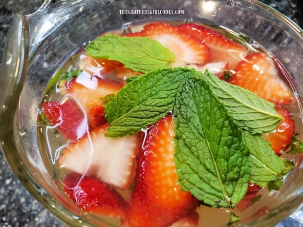 Several whole mint leaves are added to the pitcher of agua fresca.