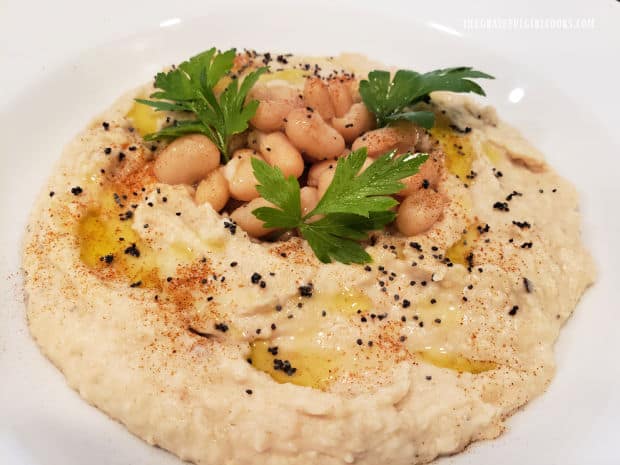 Classic cannellini bean dip is garnished with olive oil, parsley, poppy seeds and paprika.