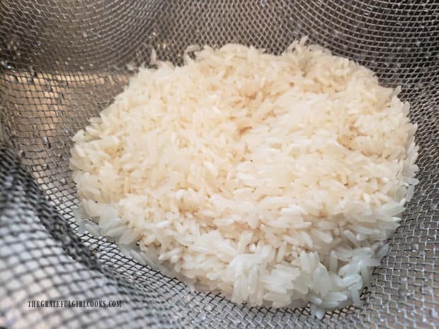 White rice is rinsed, then drained well in a wire mesh strainer.