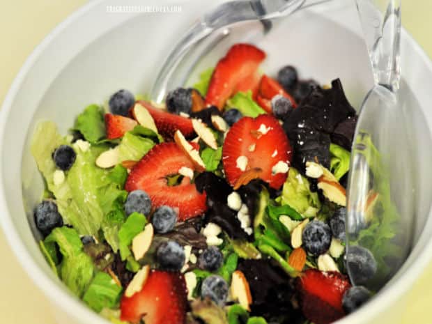A green salad with fresh fruit is complimented well with the salad dressing.