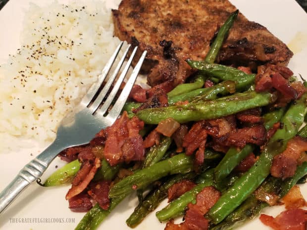 Pan-seared green beans and bacon, with pork chop and rice on the plate.
