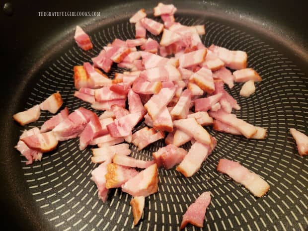 Small pieces of bacon are cooked until mostly done in large skillet.