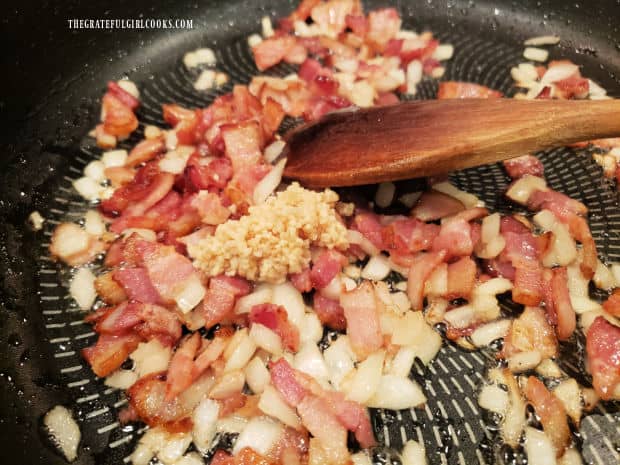 Chopped onions and minced garlic are added to the cooked bacon in skillet.