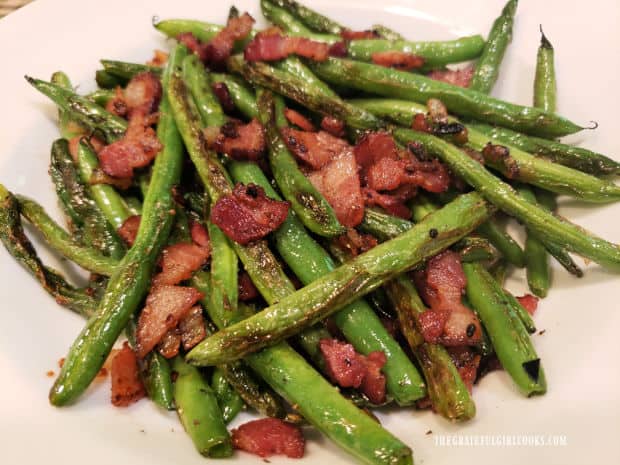 A white bowl, filled with pan-seared green beans and bacon.