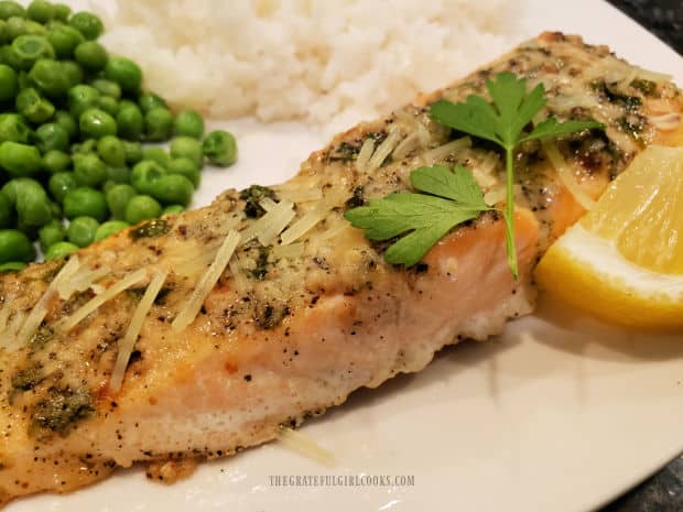 Parmesan herb baked salmon, served with rice and peas, on a white plate.