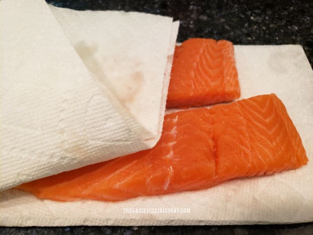 Using more paper towels to blot the excess moisture off the salmon fillets.