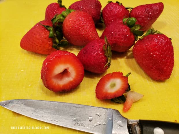Stems and cores are removed from rinsed, fresh strawberries.
