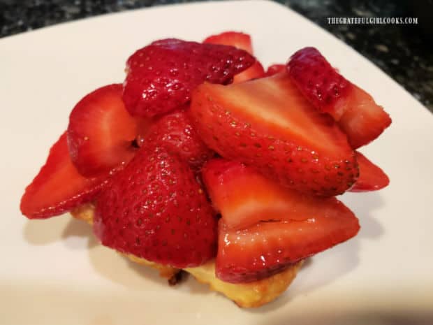 Sliced strawberries piled on the bottom half of the shortcake.