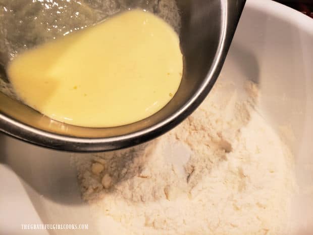 Egg mixture is added to the dry ingredients in a large white bowl.