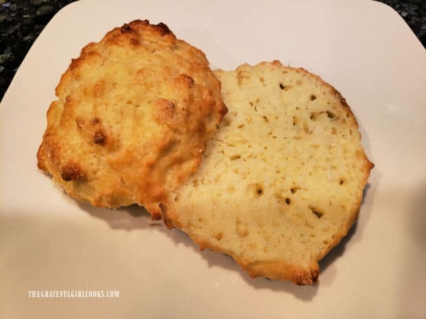 A shortcake, cut in half, on a white plate, ready for strawberry filling.