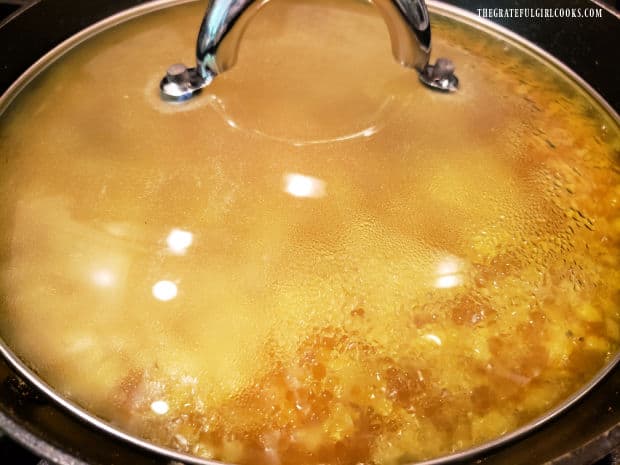 The rice is cooked, with a lid on the skillet.