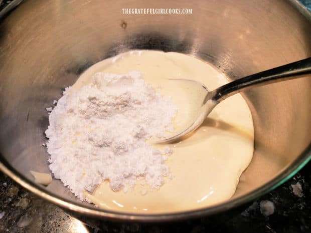 Powdered sugar, whipping cream and almond extract, in a large metal bowl.