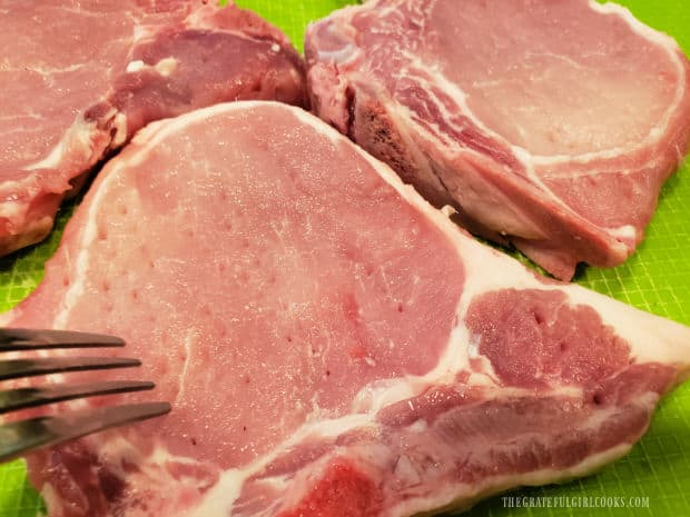 Pork chops are tenderized with the tines of a fork before marinating.