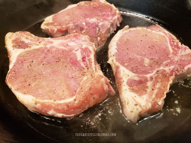 Pork chops are pan-seared in hot oil, after marinating.