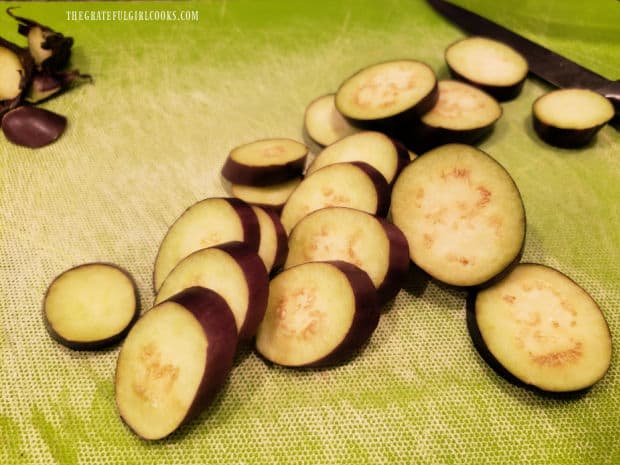 Stems are removed and thin circular slices are cut from the 3 baby eggplants.