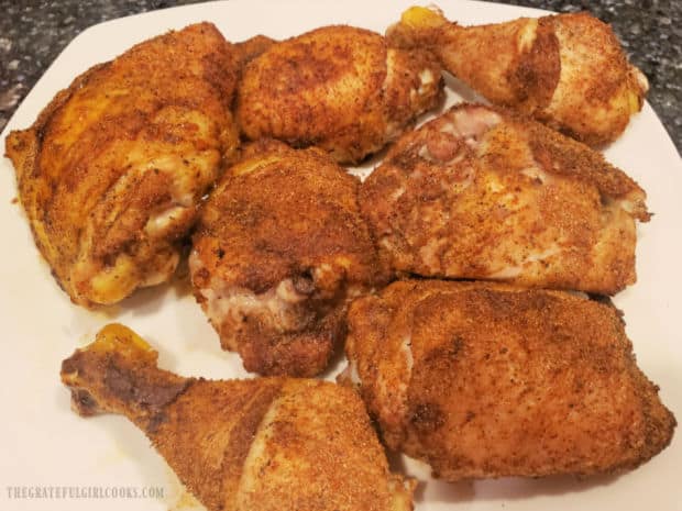 A white platter with baked chicken thighs and legs on it.