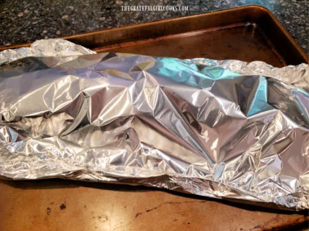 Seasoned ribs are sealed in foil packet on a baking sheet, then refrigerated.