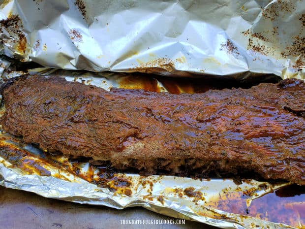 BBQ sauce is liberally applied to the baked baby back ribs.